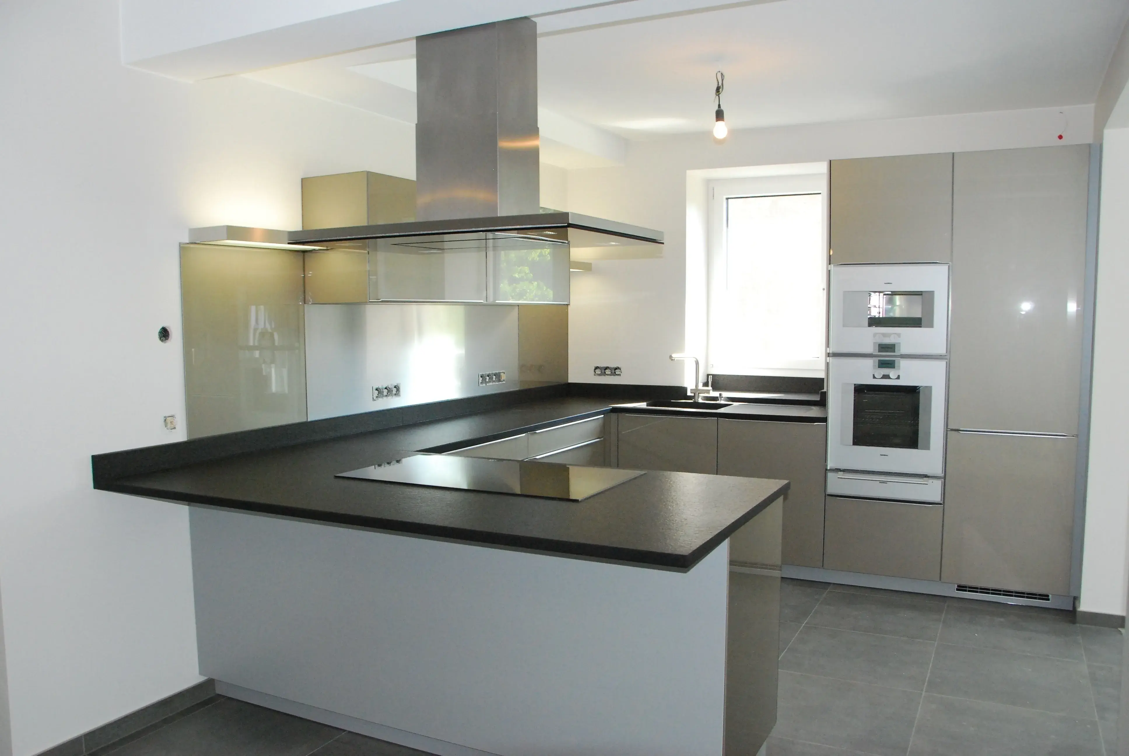Moderne Küche mit grauen Schränken, Kochinsel und großem Fenster